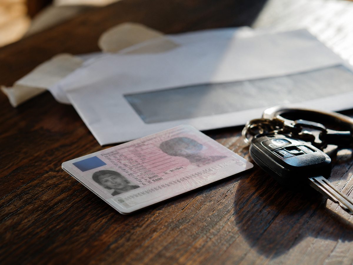 Permis de conduire français posé sur une table à côté de clés de voiture et d'un courrier administratif