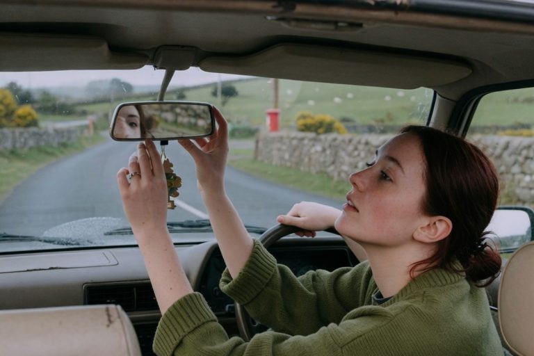 Apprentie conductrice ajustant son rétroviseur sur route irlandaise